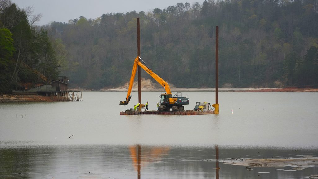 Contractors supporting the U.S. Army Corps of Engineers remove sediment from Lake Lure and the Broad River to restore navigability in support of Hurricane Helene recovery operations in Western North Carolina, April 2, 2025. Using heavy equipment such as excavators and rock trucks, crews are creating a passable waterway for barges to access and remove submerged debris. This sediment removal effort is a key step toward restoring safe conditions for the local community and facilitating long-term recovery.