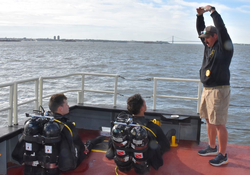 A dive-team instructor makes a point to divers just prior to entering New York-New Jersey Harbor to inspect dolphins ─ a cluster of piles driven into the ground serving as a fixed point to secure a vessel.