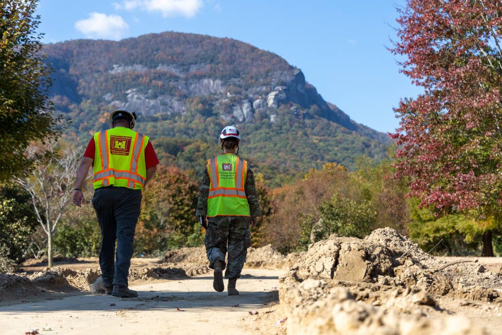 Nate Hoskins from the U.S. Army Corps of Engineers Louisville District and Maj. Brittany Hine, U.S. Army Corps of Engineers battle captain with Task Force Debris, walk along a debris-strewn path during a site assessment at Lake Lure, North Carolina, Oct. 26, 2024. The visit supports ongoing coordination with local agencies on post-storm debris removal efforts. (U.S. Army Corps of Engineers photo by Travis England)