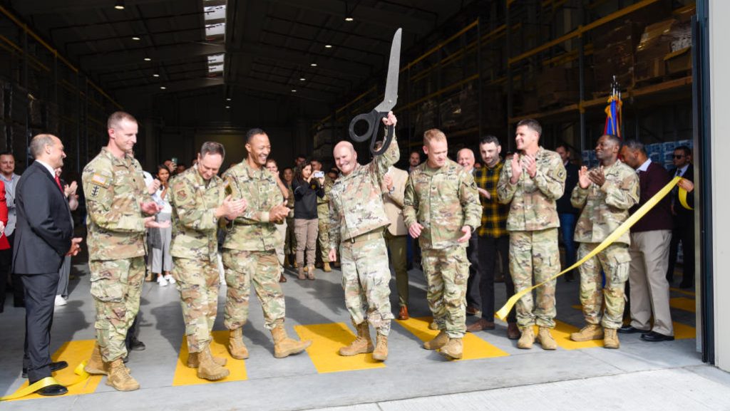 U.S. Army Gen. Christopher Cavoli, former U.S. European Command & Supreme Allied Commander happily holds up ceremonial scissors after cutting the ribbon on the new warehouse facility at Aviano Air Base in Italy with assembled senior military leaders October 9, 2024. The U.S. Army Corps of Engineers partnered with Southern European Task Force, Africa, U.S. Army Garrison Italy, the 173rd Airborne Brigade, the U.S. Air Force and others to deliver the $4.5 million warehouse project that will reduce the rapid deployment time for Soldiers by storing pre-positioned equipment and stock at Aviano Air Base. (U.S. Army photo by Rich Puckett)