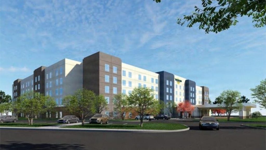 An architectural 3D rendering of a large, modern multi-story lodging facility surrounded by parking areas, green lawns, and young landscaping trees under a blue sky.