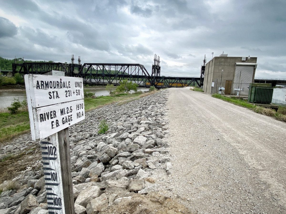 Station marker sign for the Armourdale Unit levee located adjacent to a major rail bridge in Kansas City.