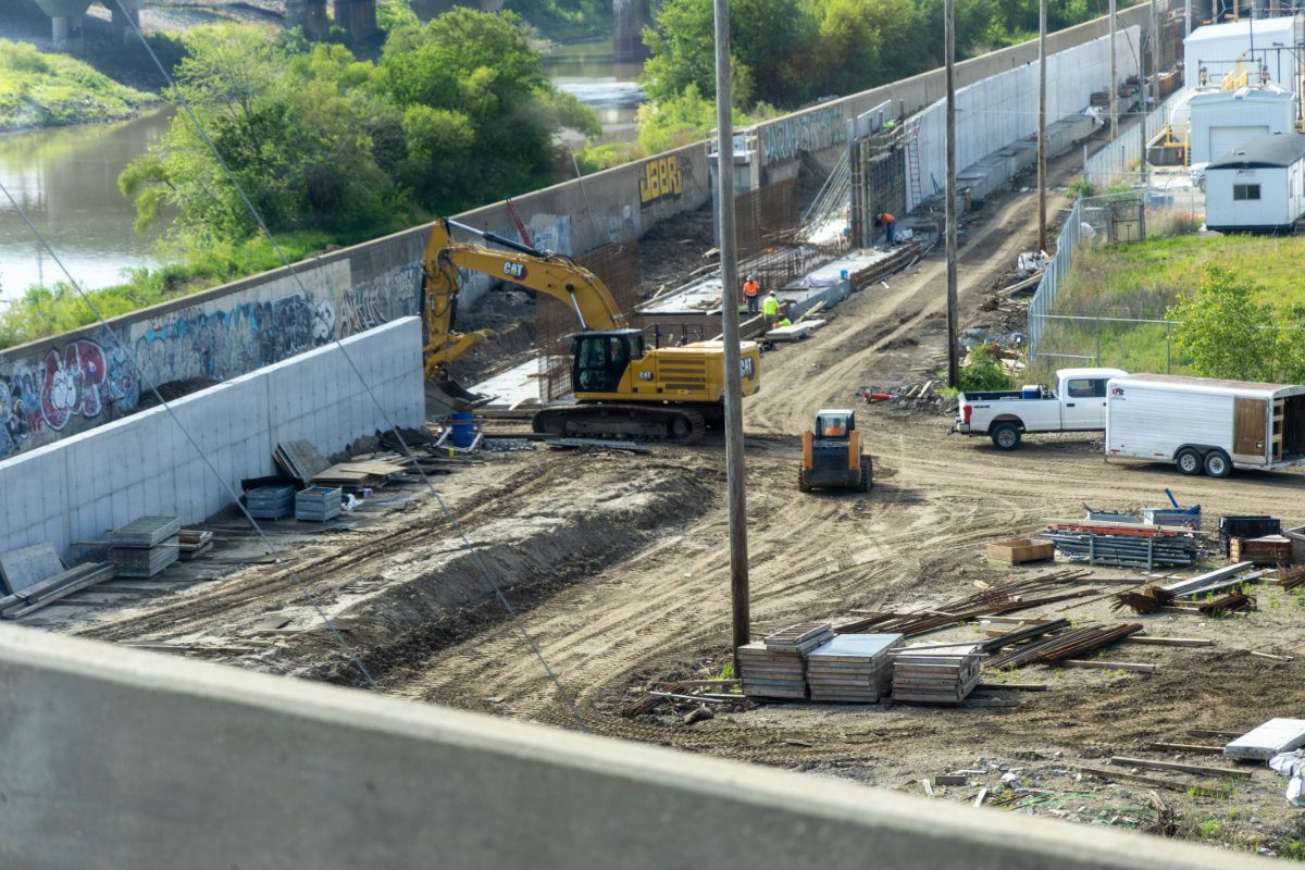 An excavator executing foundation excavation and earthwork near the Kansas River bank.