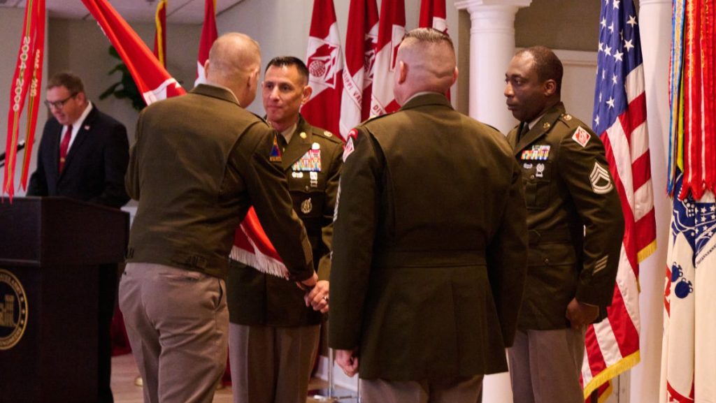 A general officer passes the red USACE organizational flag to a command sergeant major during a military change of responsibility ceremony.